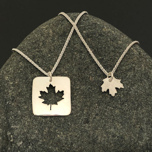 Maple-Leaf-Pendants-with-chain-side-by-side-on-stone