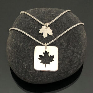Maple-Leaf-Pendants-with-chain-stacked-on-stone